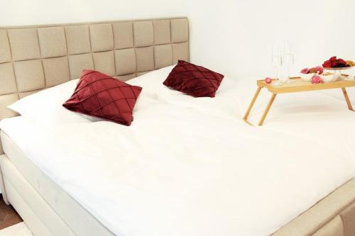 ein Bett mit zwei roten Kissen und einem Tisch darauf in der Unterkunft SECRET HIDEAWAYS cozySTUDIO 1 superior Apartment mit WiFi l 450m bis Uni l Zoo in Duisburg