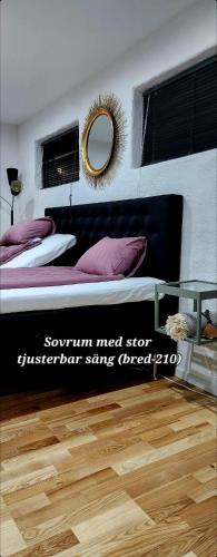 1 dormitorio con cama con almohadas moradas y espejo en ÖSTERLEN PARKEN en Simrishamn