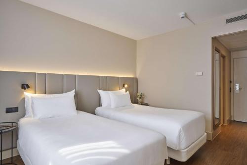 2 camas en una habitación de hotel con almohadas blancas en NH Frankfurt Airport, en Kelsterbach