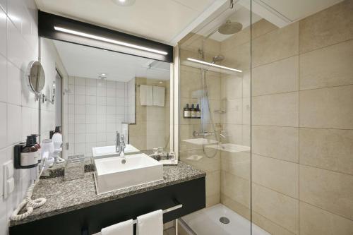 W łazience znajduje się umywalka i prysznic. w obiekcie NH Frankfurt Airport w mieście Kelsterbach