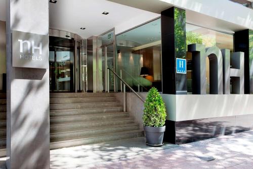 馬德里的住宿－NH馬德里普林西德維爾蓋拉酒店，一座有楼梯的建筑,前面有盆栽植物