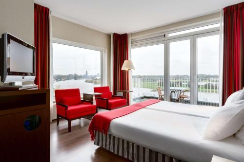 a hotel room with a bed and a large window at NH Arnhem Rijnhotel in Arnhem