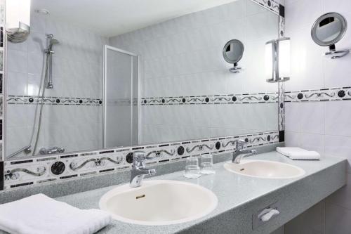 NH Arnhem Rijnhotel في آرنم: حمام به مغسلتين ومرآة كبيرة