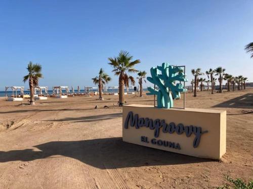 a sign on the beach with palm trees in the background at Mangroovy Ritzy, Cerulean appartement by the pool in Hurghada