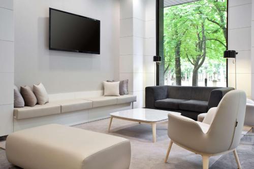 a living room with a couch and a tv on a wall at NH Canciller Ayala Vitoria in Vitoria-Gasteiz