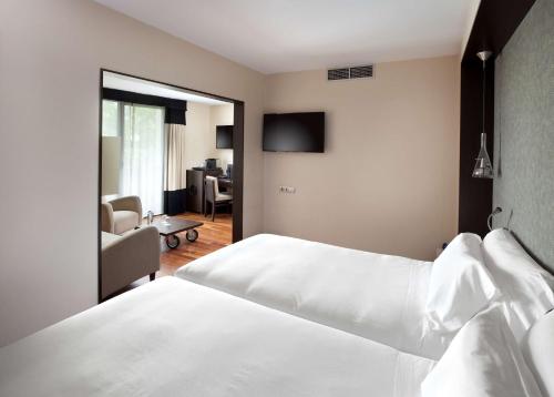 a bedroom with a bed and a living room at NH Canciller Ayala Vitoria in Vitoria-Gasteiz