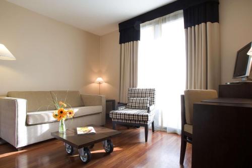 a living room with a couch and a chair at NH Canciller Ayala Vitoria in Vitoria-Gasteiz
