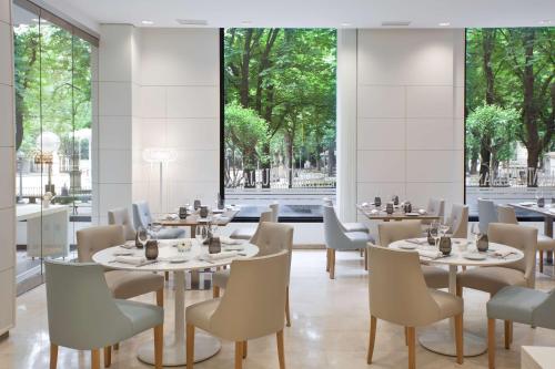 a restaurant with tables and chairs and large windows at NH Canciller Ayala Vitoria in Vitoria-Gasteiz