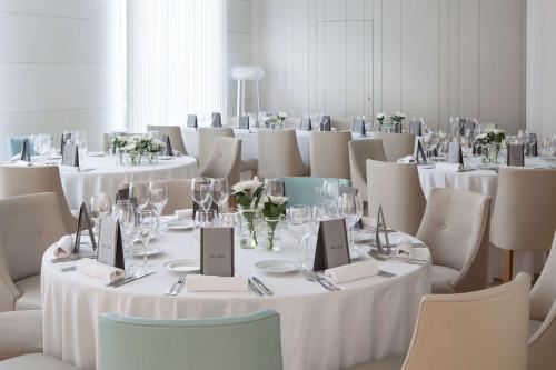 a room with tables and chairs with white tablecloths at NH Canciller Ayala Vitoria in Vitoria-Gasteiz