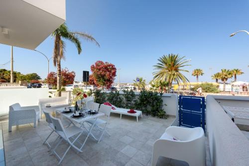 een patio met witte stoelen en tafels op een dak bij Residence Luce del Mare in San Vito lo Capo