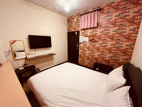 - une chambre avec un lit et un mur en briques dans l'établissement 安錤的家Angel's home, à Nangan