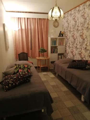 a bedroom with two beds and a table and a chandelier at Rivitalokaksio Jäppilässä in Jäppilä