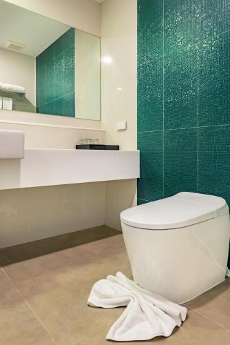 a bathroom with a white toilet and a green wall at PLAAI Prime Hotel Rayong SHA Extra Plus in Rayong