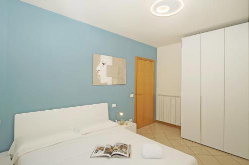 een slaapkamer met een wit bed met een tijdschrift erop bij Appartamento la Goccia - Gardagate in San Felice del Benaco