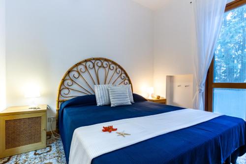 Schlafzimmer mit einem blauen Bett und einem großen Fenster in der Unterkunft Appartamento La Poesia Bilo 2 - MyHo Casa in Tortoreto Lido