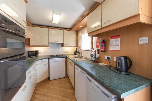 cocina grande con electrodomésticos blancos y armarios de madera en Cobblestones Cottage at Lovelady Shield, en Alston