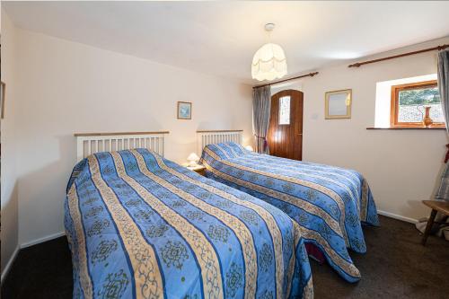 a bedroom with two beds with blue and yellow blankets at Cobblestones Cottage at Lovelady Shield in Alston