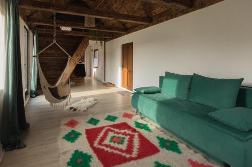 a living room with a green couch and a rug at Organicle Lodge in Sîncrăieni