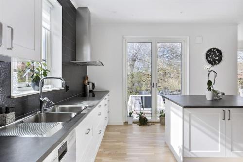 a white kitchen with a sink and a window at Modernt hus med parkeringsplatser och trädgård in Gothenburg