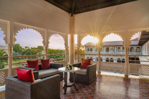 Habitación con 2 sillas y balcón con mesa. en Holiday Resort & Spa A Unit of S Poddar Group, en Gandhidham