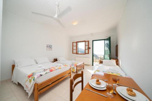 Myrtos View Apartments في Anomeriá: غرفة نوم بسرير وطاولة مع كرسيين