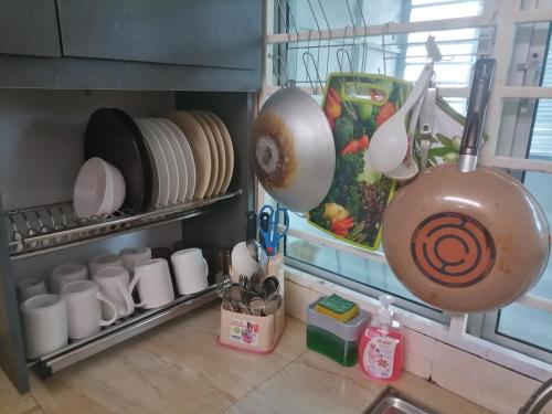 a kitchen with dishes and utensils hanging from a shelf at D'Indah59 KLIA Homestay in Sepang