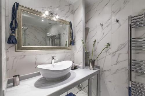ein weißes Badezimmer mit einem Waschbecken und einem Spiegel in der Unterkunft Luxury Acropolis View Duplex Penthouse in Thiseio 155m2 in Athen