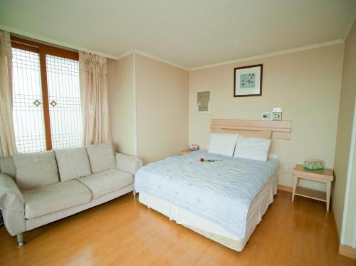 a bedroom with a bed and a couch at Hotel Good Inn in Seogwipo