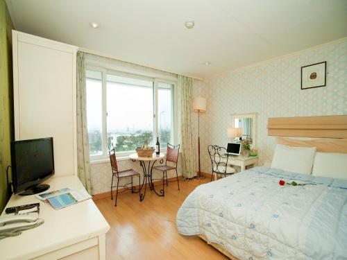 1 dormitorio con 1 cama y 1 mesa con sillas en Hotel Good Inn, en Seogwipo