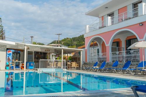 a swimming pool in front of a building with blue chairs at Stella Studios in Argasi