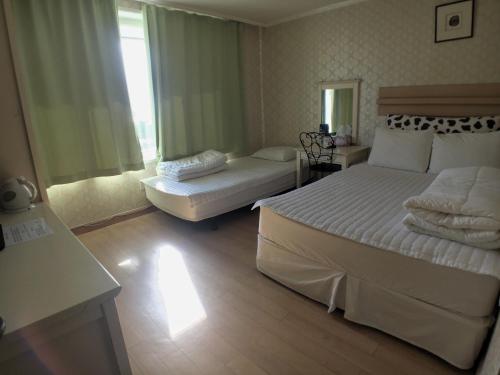 a hotel room with two beds and a window at Hotel Good Inn in Seogwipo