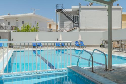 a large swimming pool with blue tables and chairs at Stella Studios in Argasi