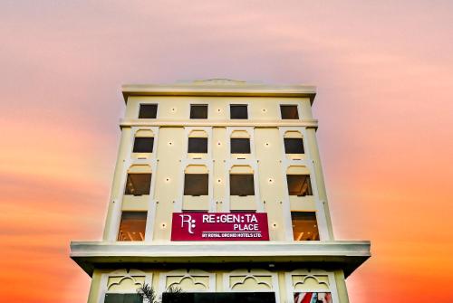 a tall white building with a pink sign on it at Regenta Place Jhansi by Royal Orchid Hotels Limited in Jhānsi