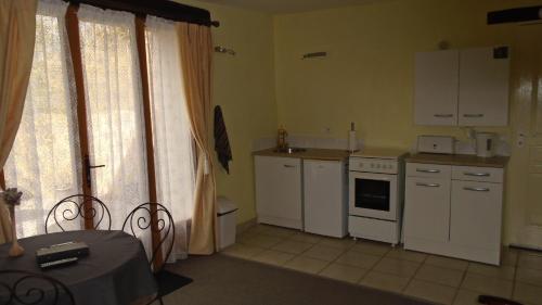 une petite cuisine avec des appareils électroménagers blancs et une table dans l'établissement Mouhet Appartement Sortie 21 A20, à Mouhet