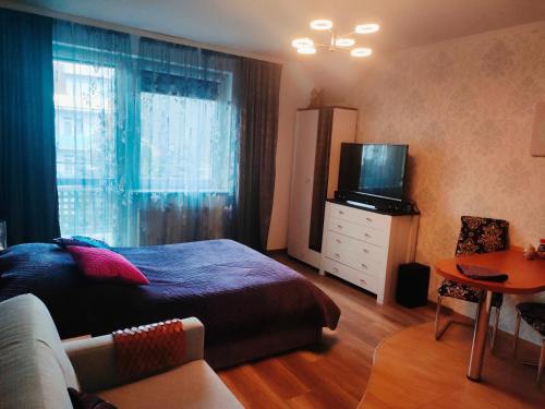 a bedroom with a bed and a television and a table at Apartament Klonowa in Kołobrzeg