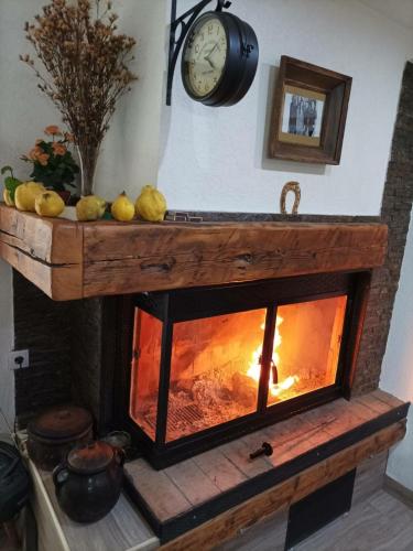 a fireplace with a hearth and a clock on the wall at Vila KTM Lisine in Despotovac