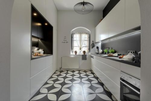 a kitchen with white cabinets and a black and white floor at Coat of Arms Mansion in Fira
