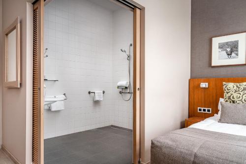 a bedroom with a bed and a bathroom with a shower at Hotel De Pupiter in Kluisbergen
