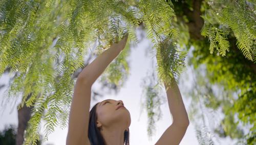 Una donna che si avvicina ad un albero con le braccia in aria di Botania Relais & Spa - The Leading Hotels of the World a Ischia