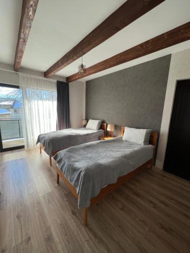 a bedroom with two beds and a large window at Galash-R in Mestia