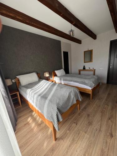 two beds in a room with wooden floors at Galash-R in Mestia