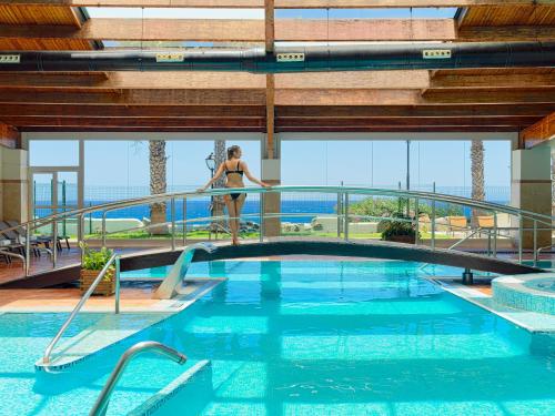 a woman walking on a rail next to a swimming pool at H10 Rubicón Horizons Collection in Playa Blanca