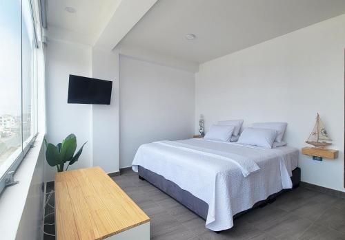 a white bedroom with a bed and a tv at ALTEA HOTEL - San Bartolo in San Bartolo