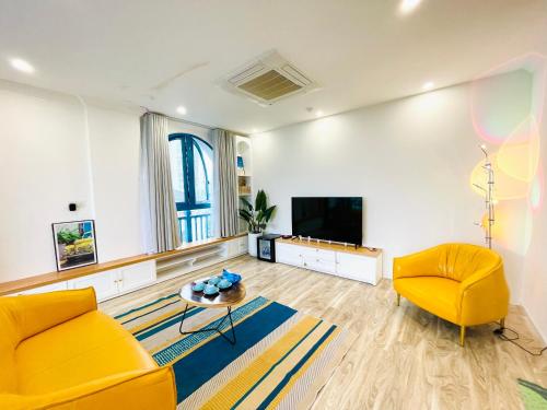 a living room with two yellow chairs and a flat screen tv at Santori Hotel And Spa in Da Nang