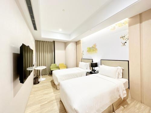 a hotel room with two beds and a tv at 台南星鑽國際商旅 Hua Hotel in Tainan