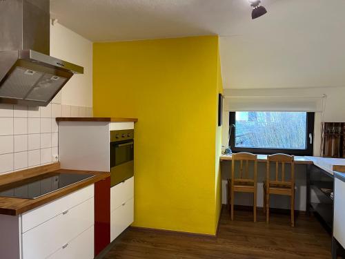 una cocina con una pared amarilla y una mesa en Wald Panorama Appartement, en Battenberg