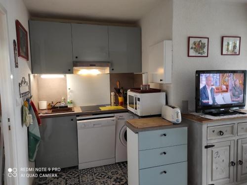 une cuisine avec des placards blancs et une télévision sur un comptoir dans l'établissement MAISON VALRAS PLAGE, à Valras-Plage