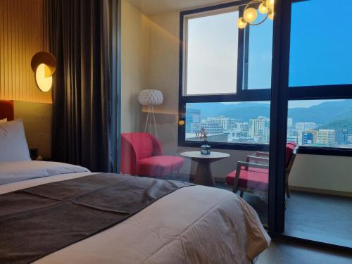釜山にあるHound Hotel Junggwanのベッドと大きな窓が備わるホテルルームです。
