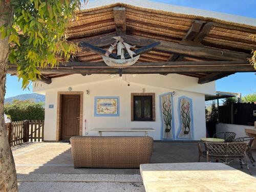 a patio with a table and chairs under a wooden ceiling at Orosei RE - Villa Samuela a 50 m dal mare in Orosei