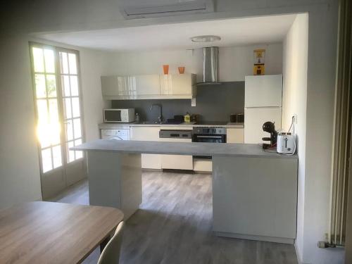 une cuisine avec des armoires blanches et un comptoir dans l'établissement Le chant de la sorgue, à LʼIsle-sur-la-Sorgue